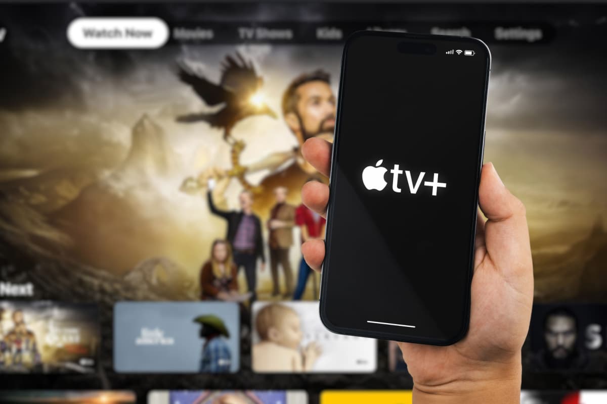Imagem do aplicativo Apple TV+ com uma televisão ligada ao fundo.