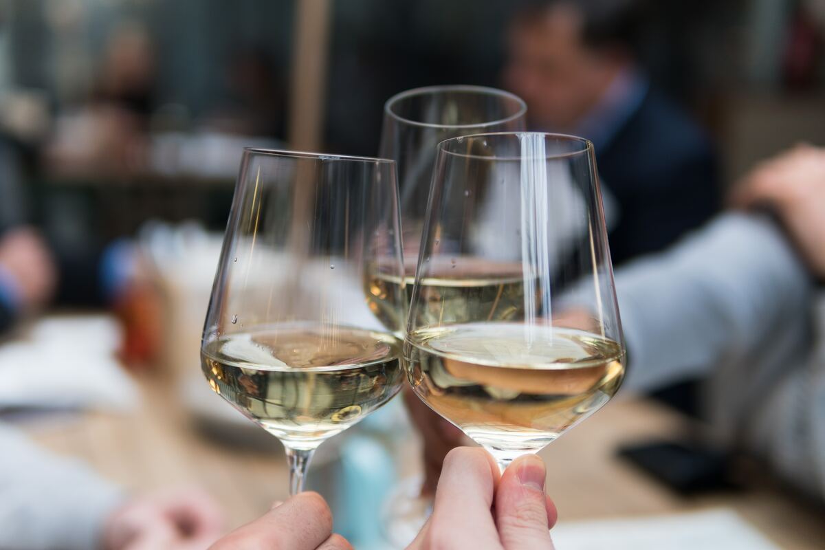 Imagem de três taças de vinho branco se tocando