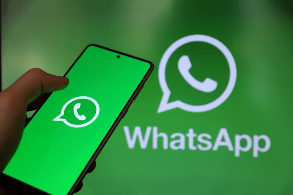 Mão segurando celular com o WhatsApp aberto e fundo também do WhatsApp