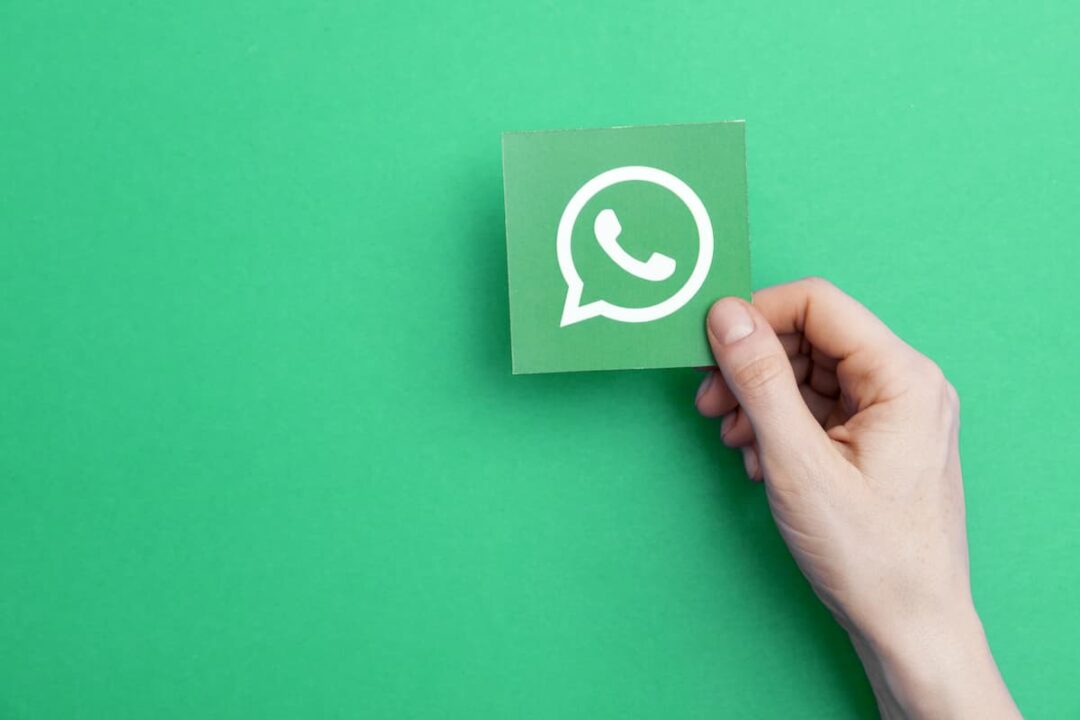Mão segurando pedaço de papel com a logo do WhatsApp