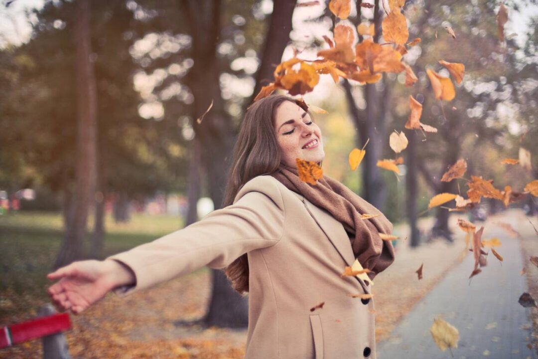 Mulher com casaco marrom com folhas ao redor